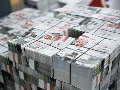 Beilagen, Prospekte, Nussbaum Medien Mehrere Stapel von Beilagenprospekten, die mit Bändern zusammengehalten werden.
