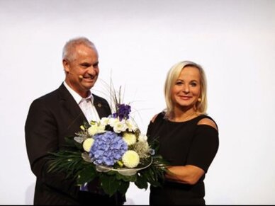 Klaus Nussbaum überreicht seiner Schwester Brigitte Nussbaum auf der Fusionierungsfeier einen Blumenstrauß.