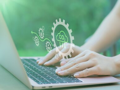 Bundesverband Druck und Medien Eine Person tippt auf einer Laptop-Tatstatur herum. Als Hologramm sieht man Zahnräder mit verschiedenen Formeln und Symbolen.