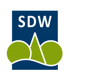Schriftzug "SDW" in weißer Schrift auf dunkelblauem Hintergrund, darunter illustrierte Bäume aus Dreiecken und Kreisen. 