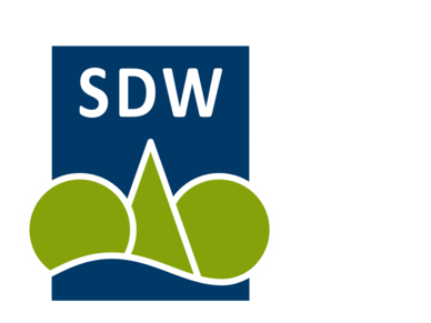 Schutzgemeinschaft deutscher Wald Schriftzug "SDW" in weißer Schrift auf dunkelblauem Hintergrund, darunter illustrierte Bäume aus Dreiecken und Kreisen.