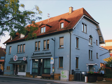 Nussbaum Medien Bad Rappenau Ein längliches hellblaues Haus mit rot-braunem Dach, an der Fassade der Schriftzug "Druckerei Stein".
